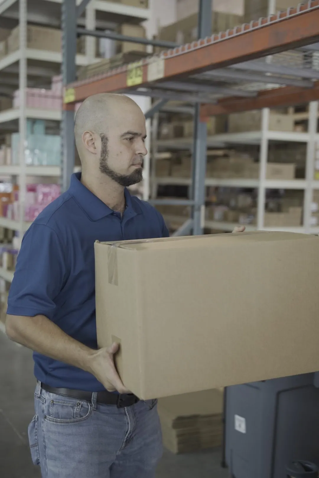 Integrante del equipo de Shoppex llevando la caja de un pedido en el almacén