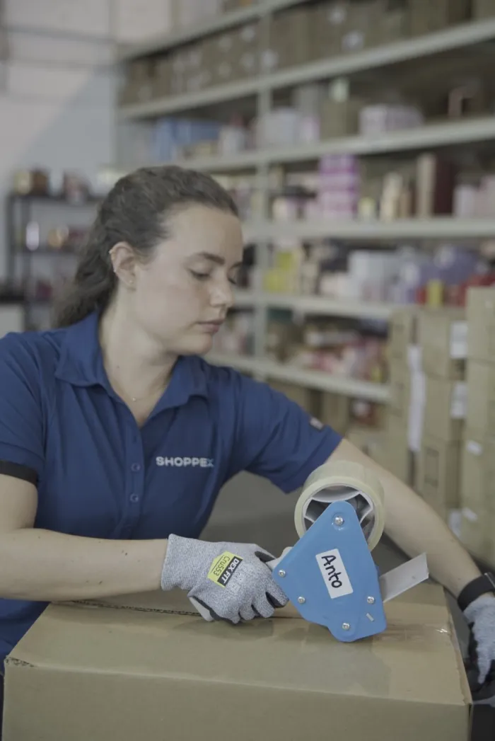 Integrante del equipo de Shoppex sellando la caja de un pedido