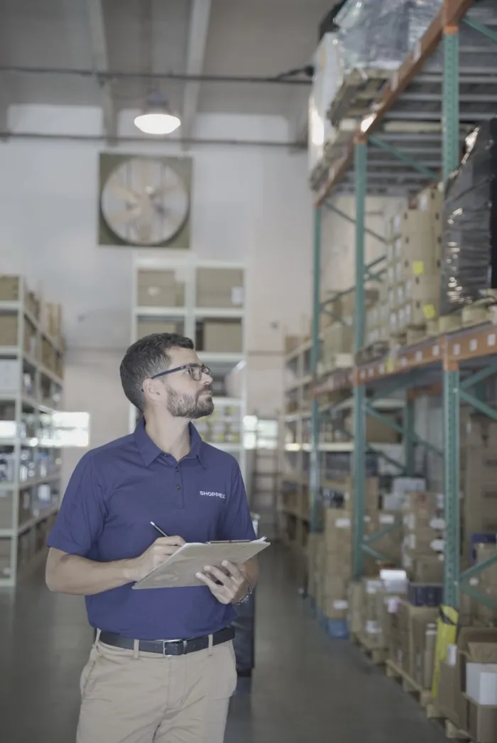 Integrante del equipo de Shoppex revisando el inventario entre los estantes del almacén